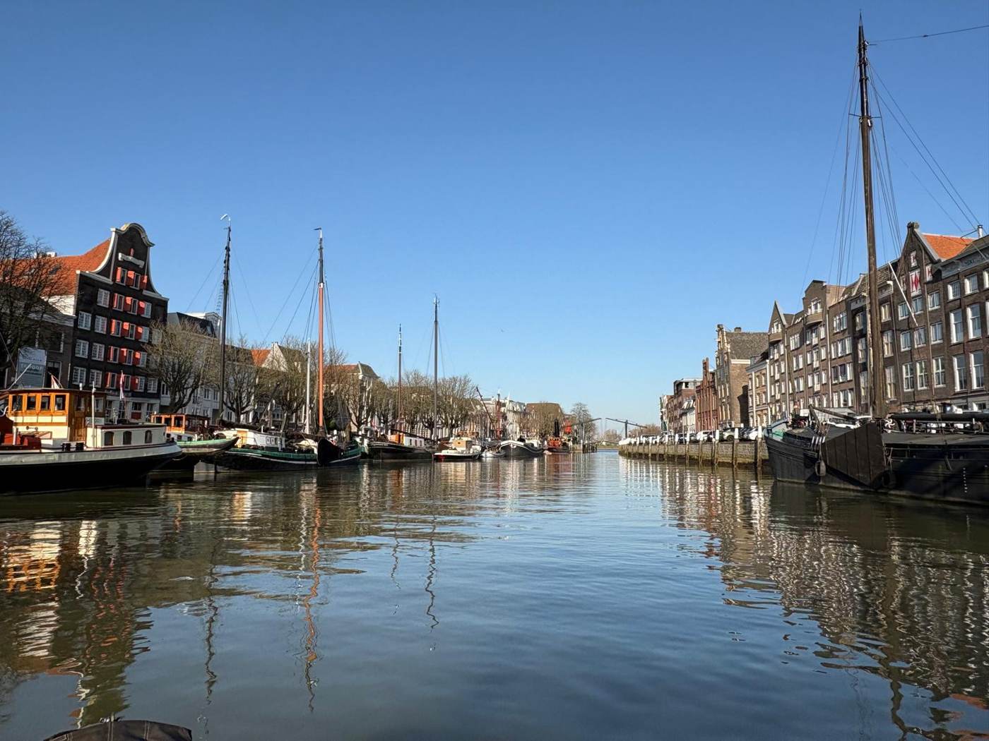 Een haven in Dordrecht met oude zeilschepen en een strakblauwe lucht