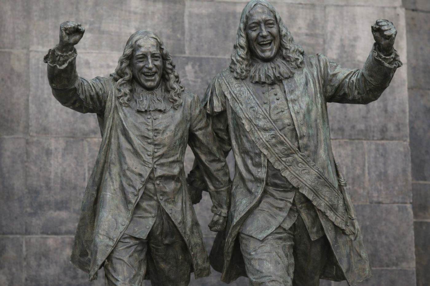 Bronzen beeld van twee mannen in zeventiende-eeuwse kleding die juichend hun armen opsteken