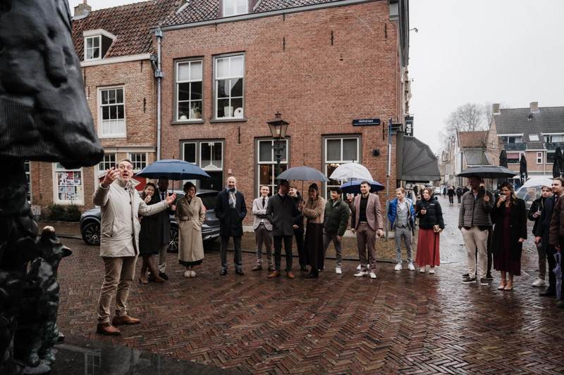 De gids voor een grote groep met paraplu's op een plein