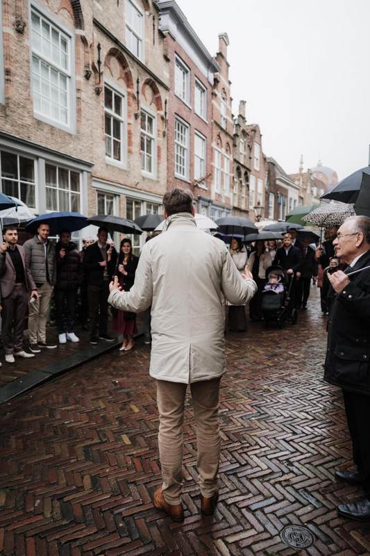 De gids spreekt een grote groep met paraplu's toe in een smalle straat
